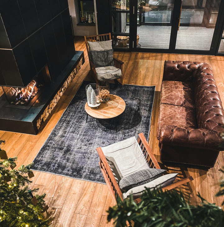 In the middle of the cozy living room, bathed in warm sunlight filtering through the window, is a nice 7x10 area rug. The cozy furniture placed around the rug c