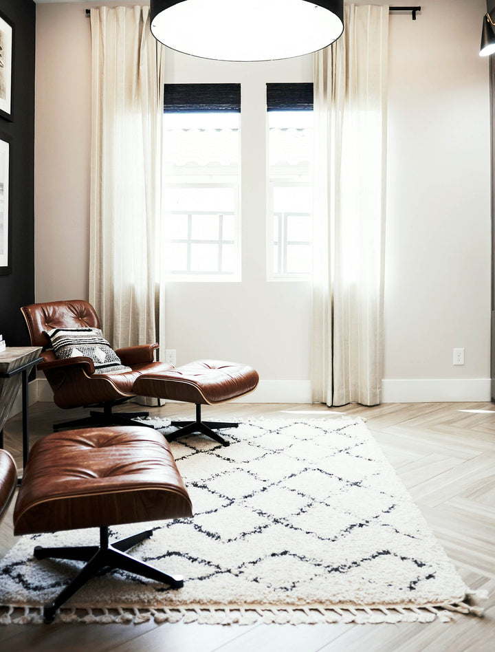 A stylish, modern room featuring a set of 6x9 rugs in white and black, arranged thoughtfully to showcase their versatility. The room is furnished with sophistic