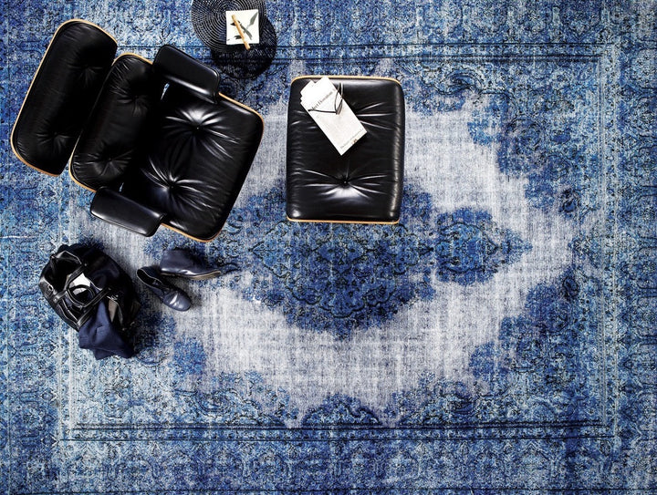 The living room boasts a stylish vintage area rug in blue tones, elegantly positioned with comfortable yet sophisticated furniture. From this bird's eye view, t