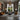 The picture depicts a large living room in modern style with an elegant layout. The room has high ceilings and one large modern metal lighting. The walls are pa